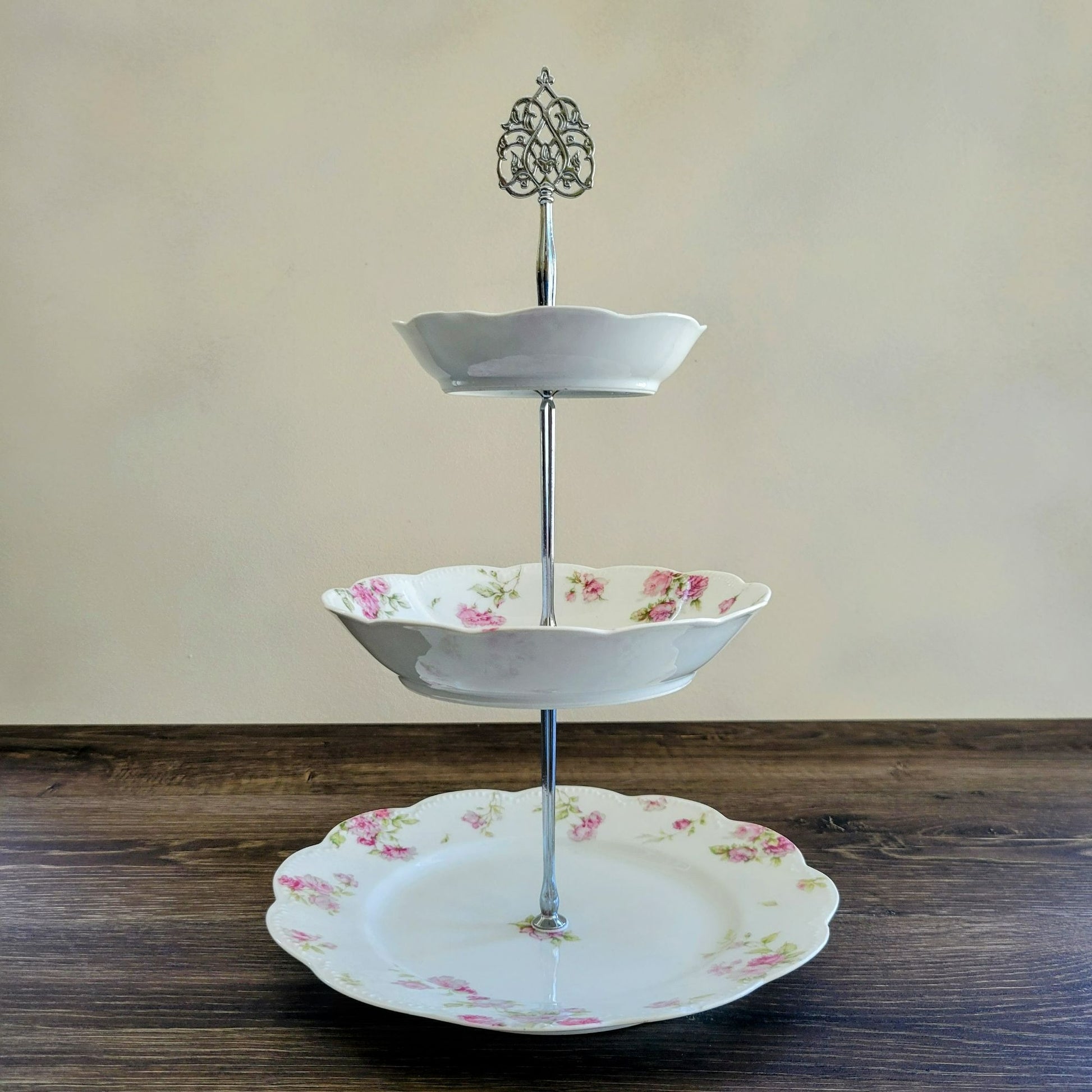 Three-tiered ceramic stand with floral design on a wooden surface